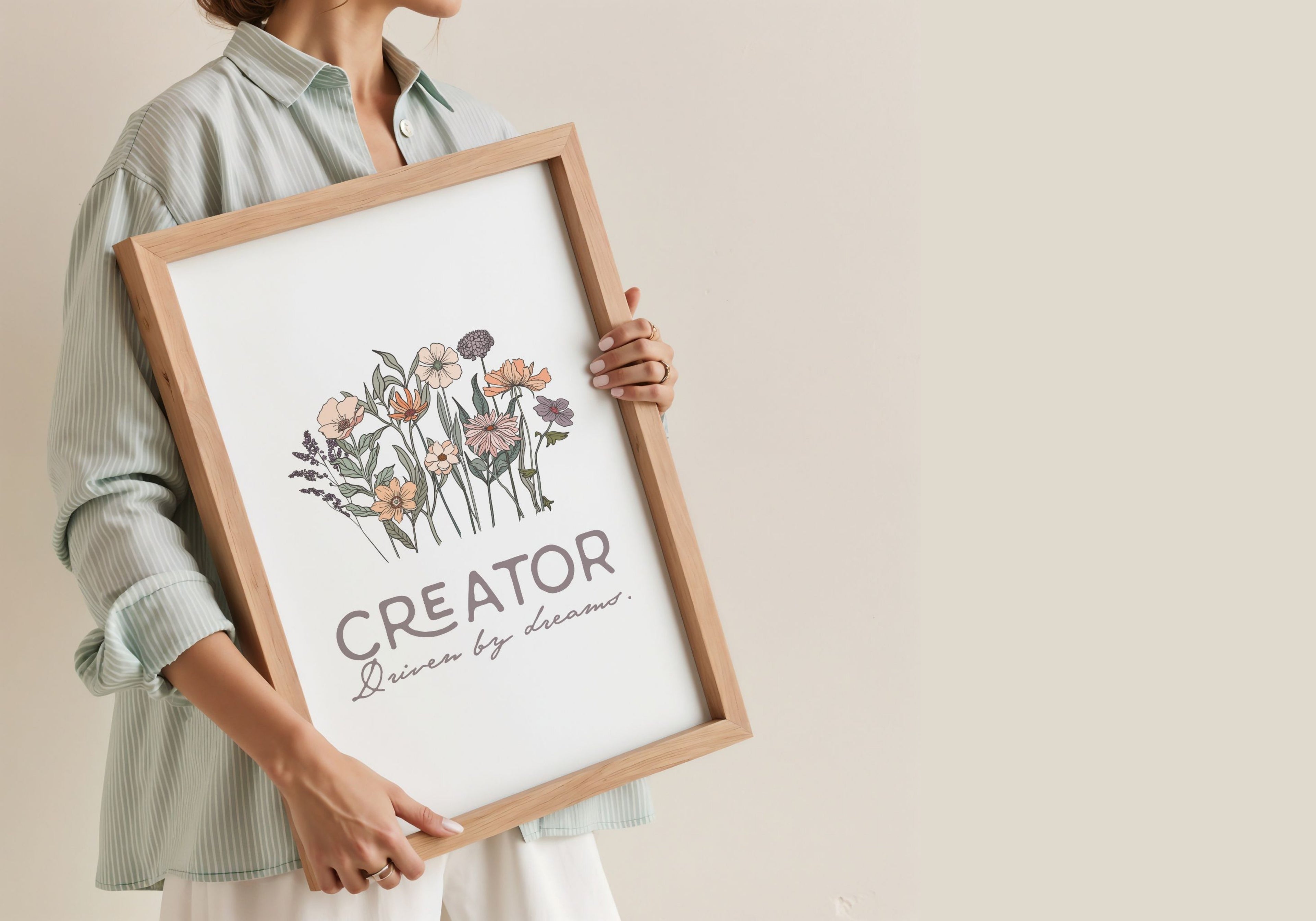 Person holding a framed artwork with floral design and text 'Creator' on a beige background