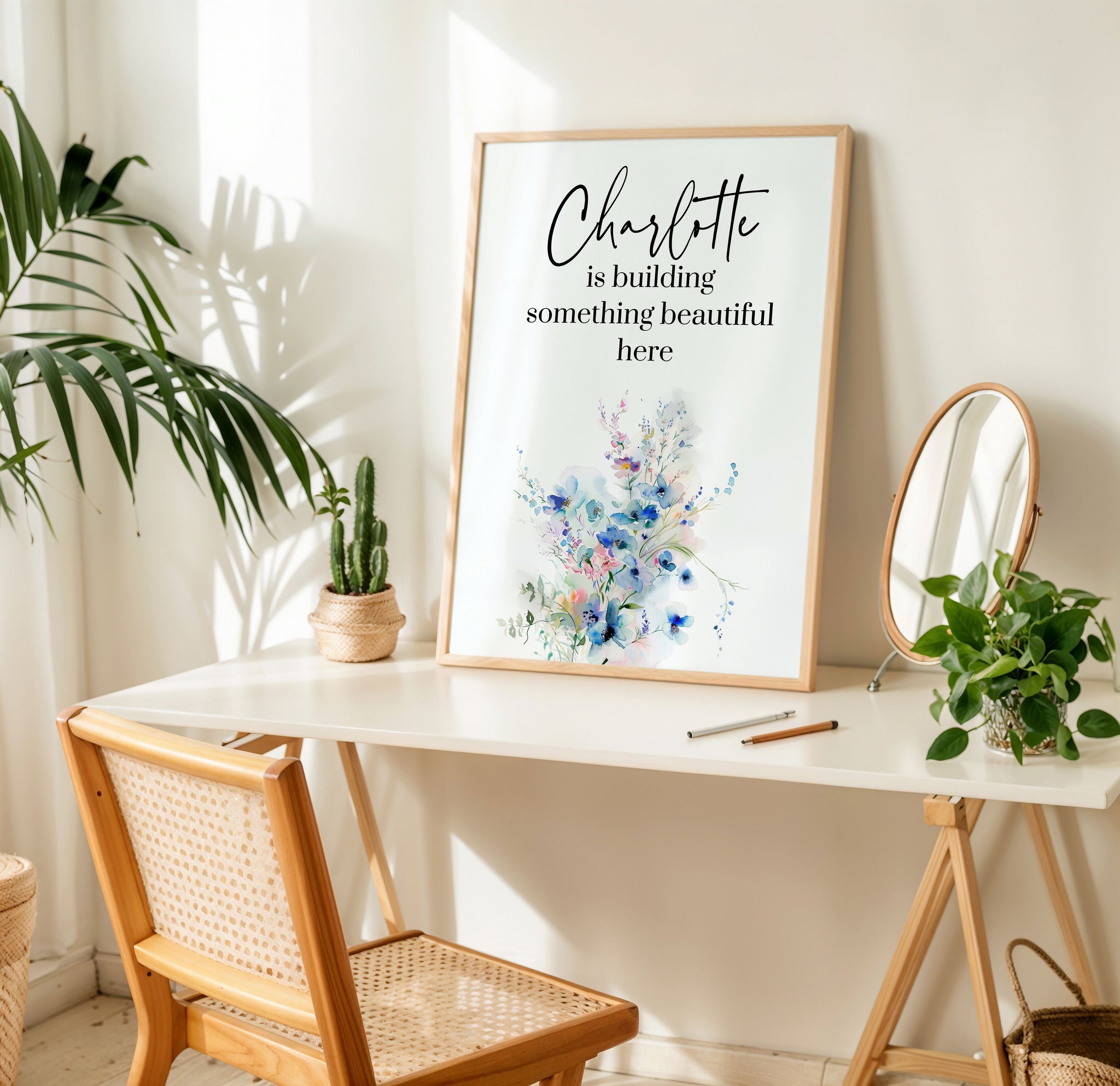 Framed artwork on a table with plants and a chair in a bright room