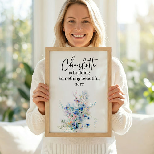 Woman holding a framed print with text and floral design