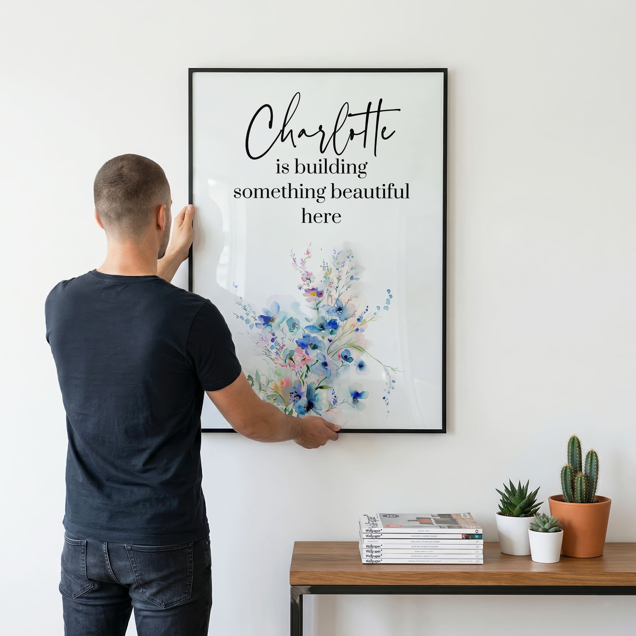 Man hanging a framed print with motivational quote on a wall.