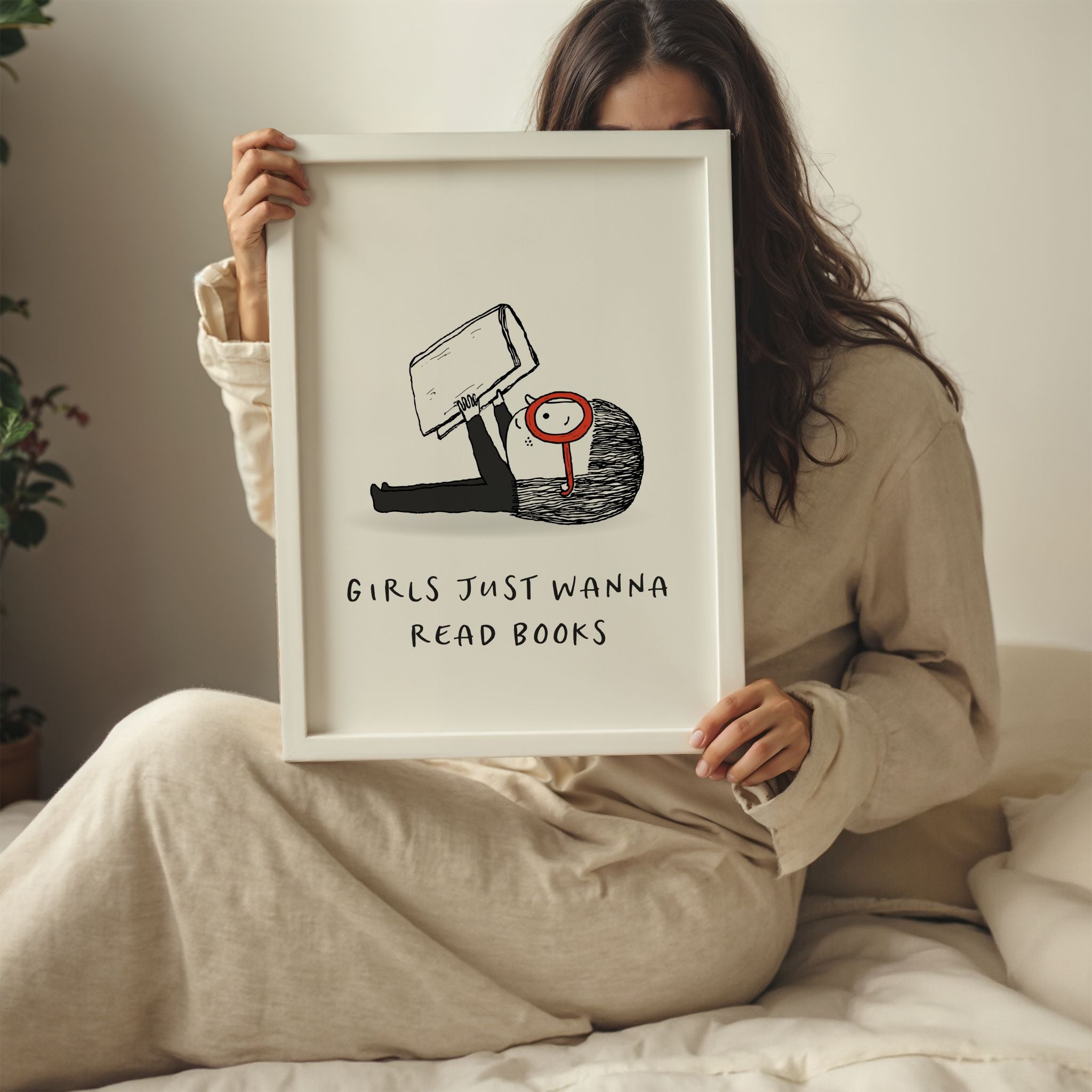 Young woman holding a framed print with a cartoon character and text 'Girls just wanna read books' in a bedroom