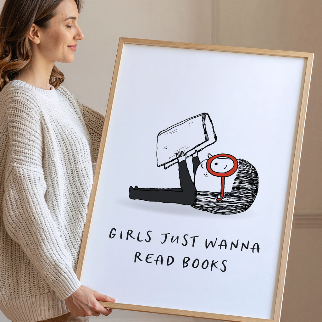 Smiling woman holding a framed print with a black and white illustration and text 'Girls Just Wanna Read Books'.