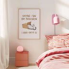Bedroom with pink nightstand, lamp, and framed cat procrastination poster above bed