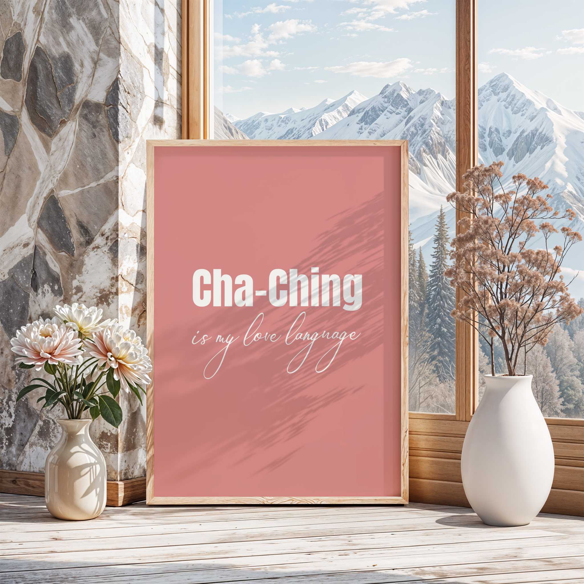 Framed poster with 'Cha-Ching is my love language' text on a pink background, placed in a room with a window view of mountains.
