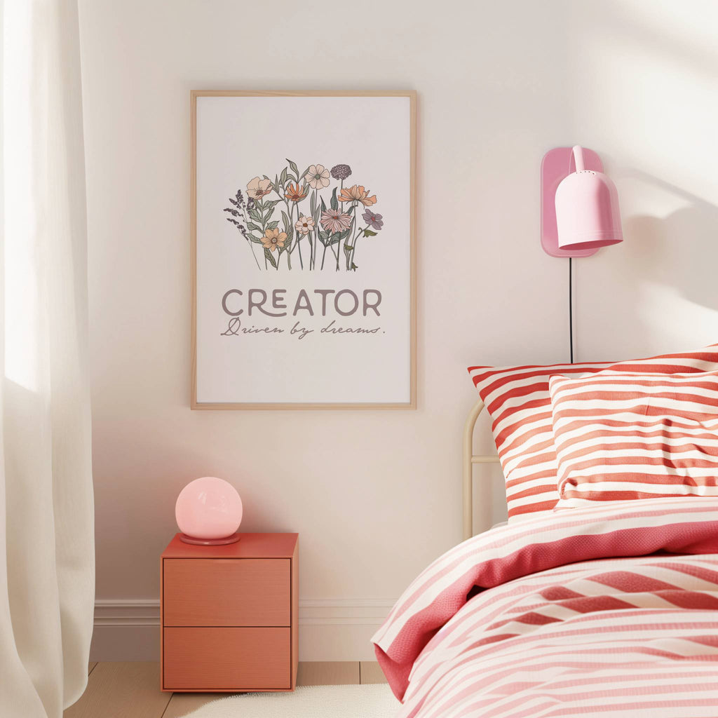 Bedroom with pink and white striped bedding, nightstand, and wall art with text 'Creator Driven by dreams.'