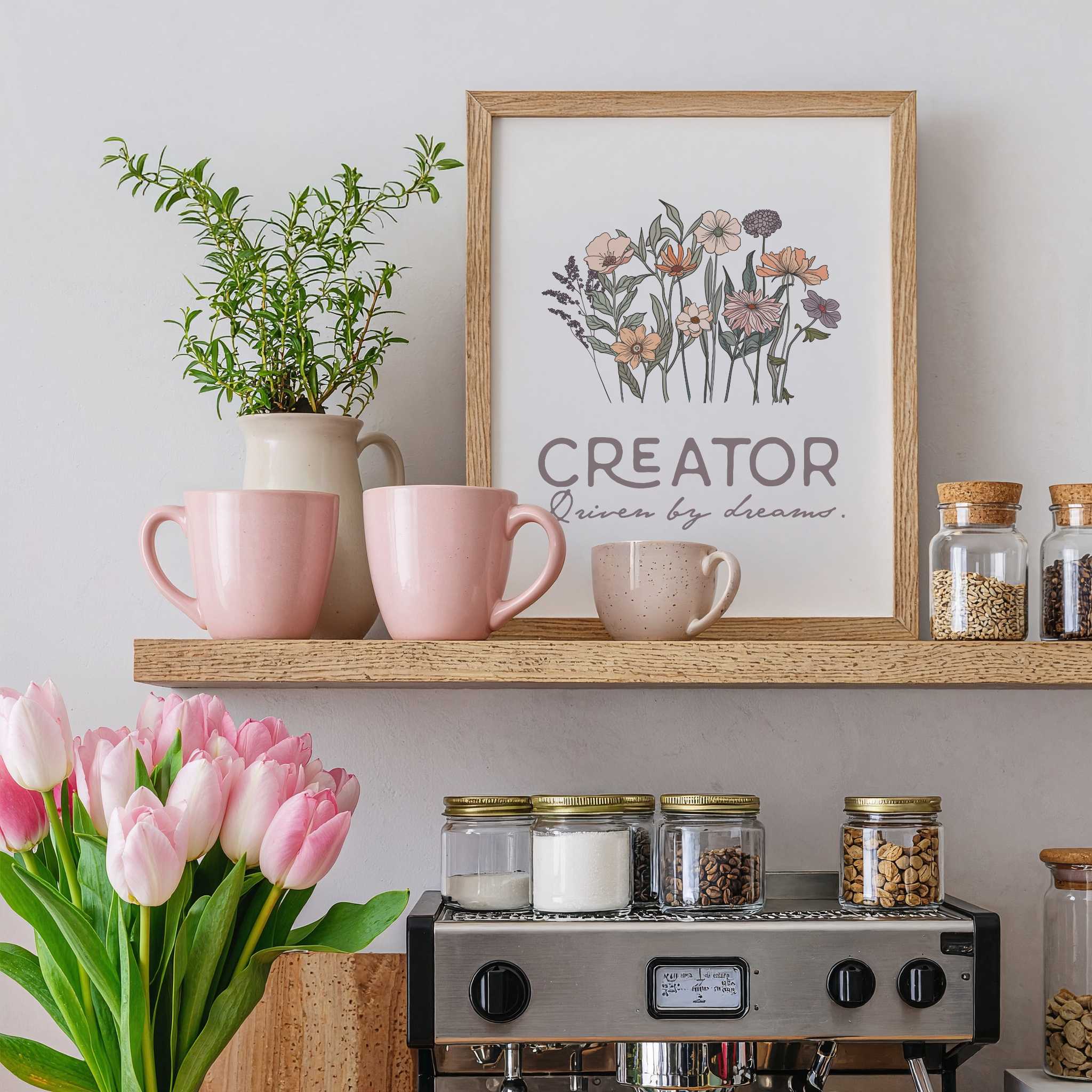Decorative shelf with pink mugs, a plant, jars, and  a framed print with the text "Creator",  on a light gray wall.