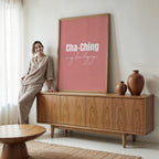 Woman standing next to a wooden cabinet with a pink framed poster in a living room.