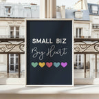 Framed poster with 'Small Biz Big Heart' text and colorful hearts on a balcony with European cityscape background
