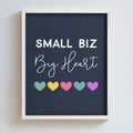 Framed artwork with 'Small Biz Big Heart' text and colorful hearts on a dark navy background.