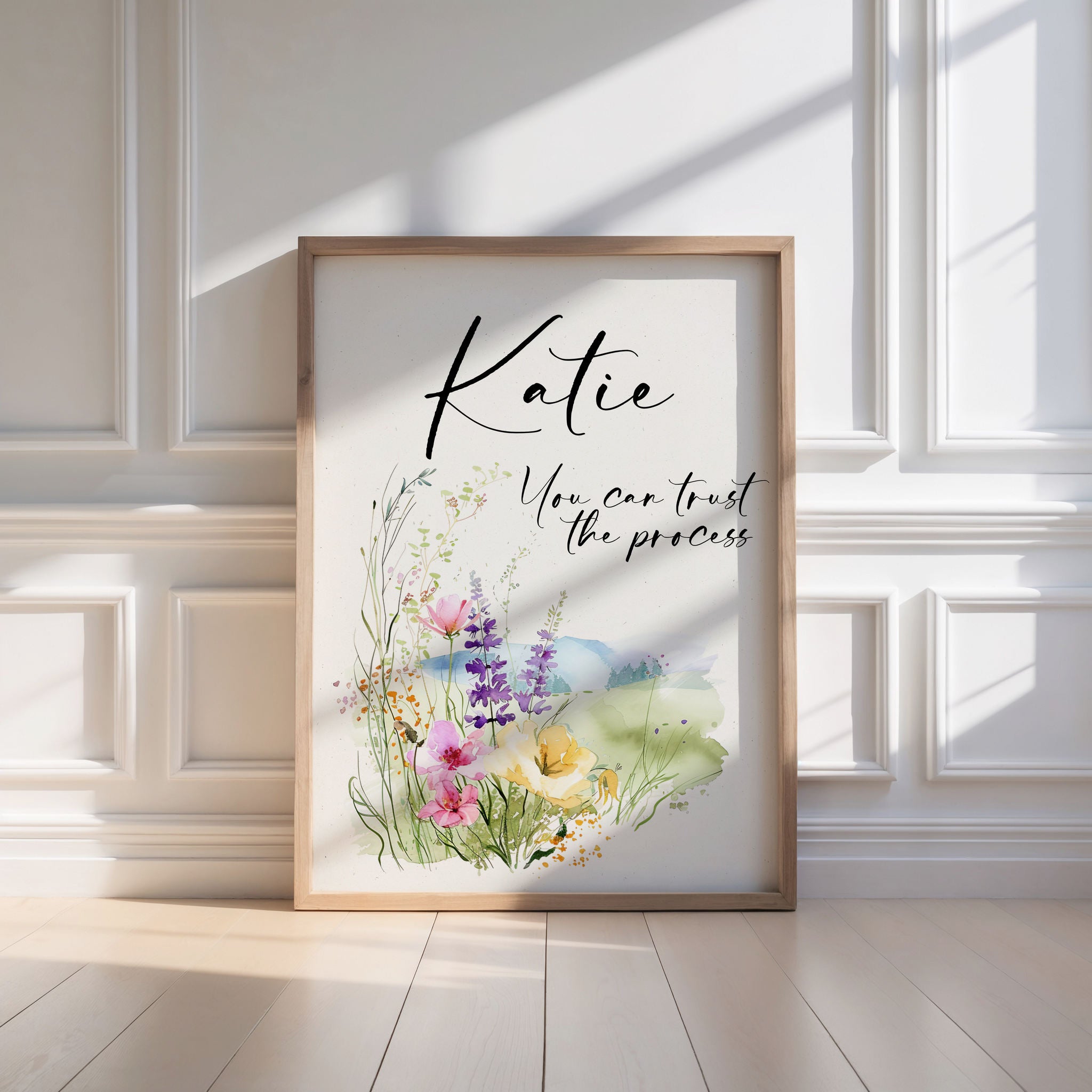 Framed artwork with floral design and text leaning against a wall.