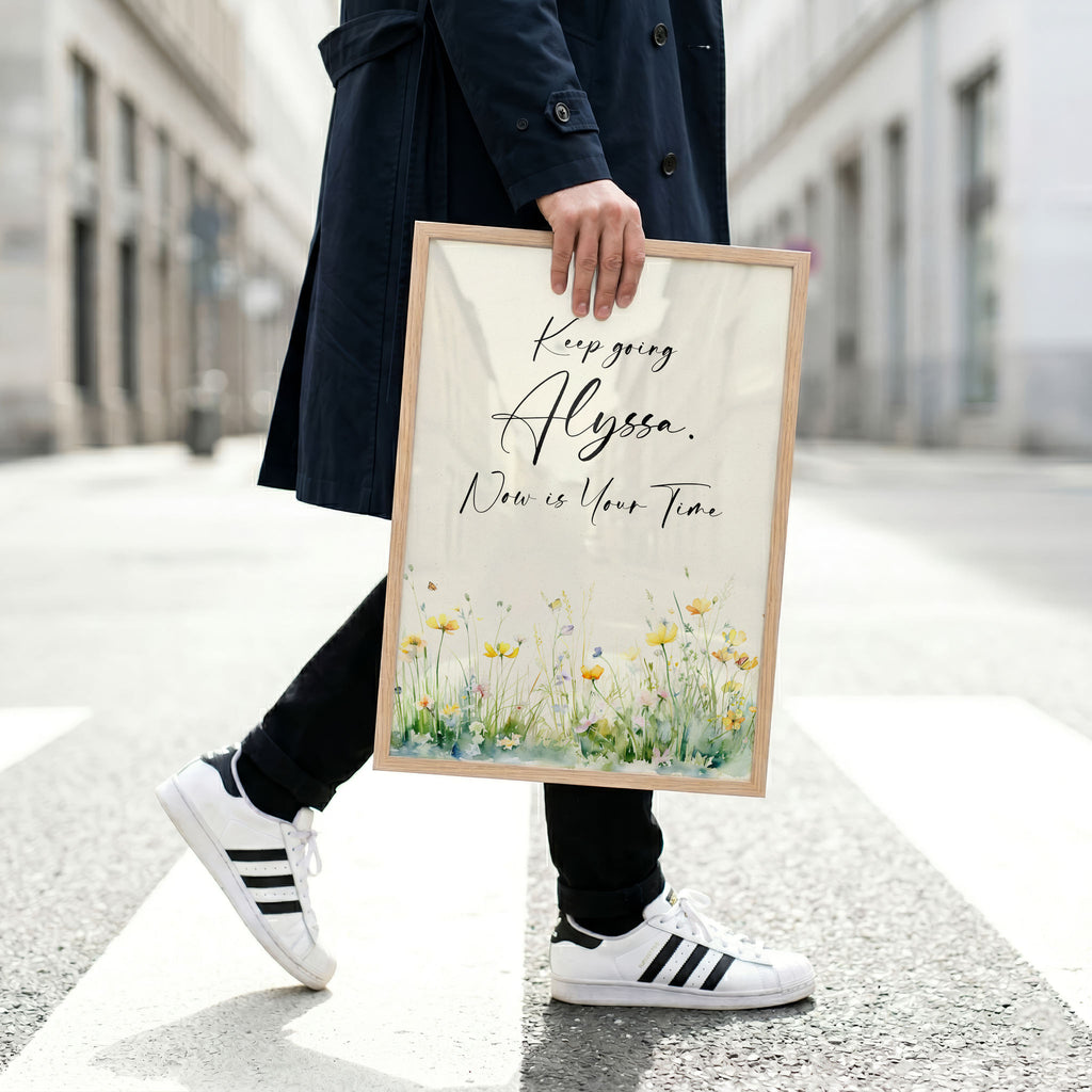 Man in navy coat and running shoes holding a framed motivational art piece