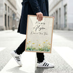 Man in navy coat and running shoes holding a framed motivational art piece